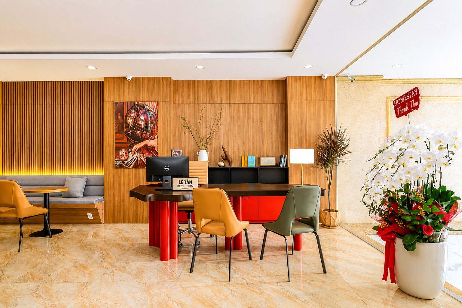 Zona de recepción de un hotel, con mostrador, asientos y una planta decorativa.