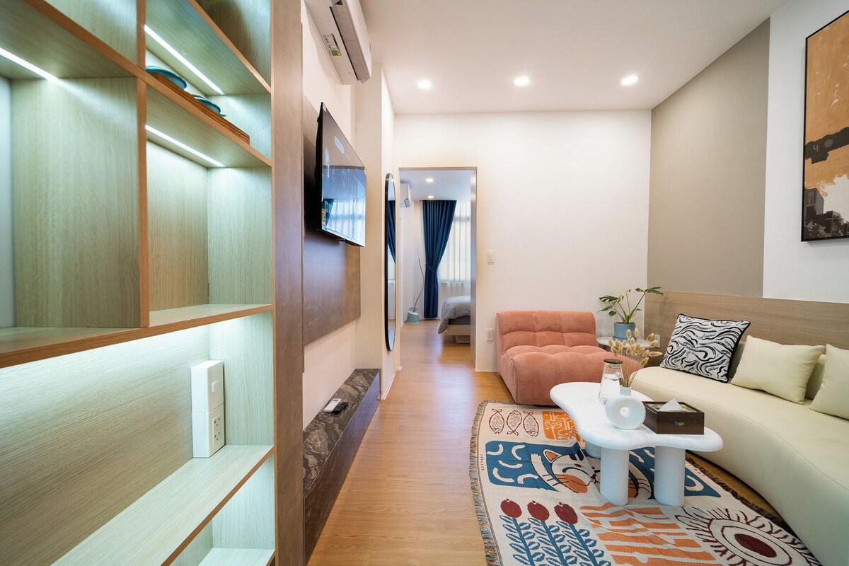A modern living room with a sofa, a coffee table, and a TV mounted on the wall.