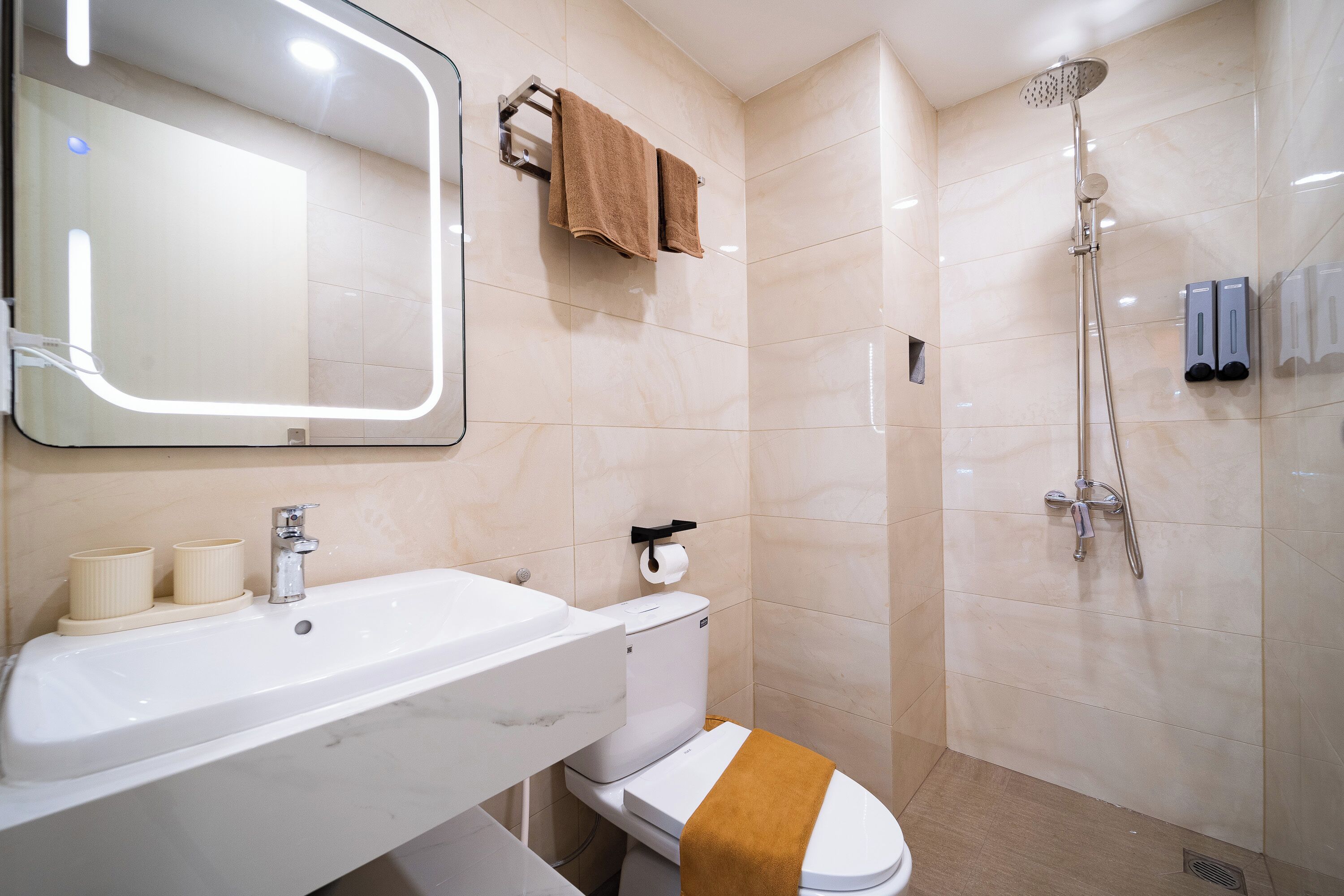 A bathroom with a sink, toilet, mirror, towel rack, and shower.