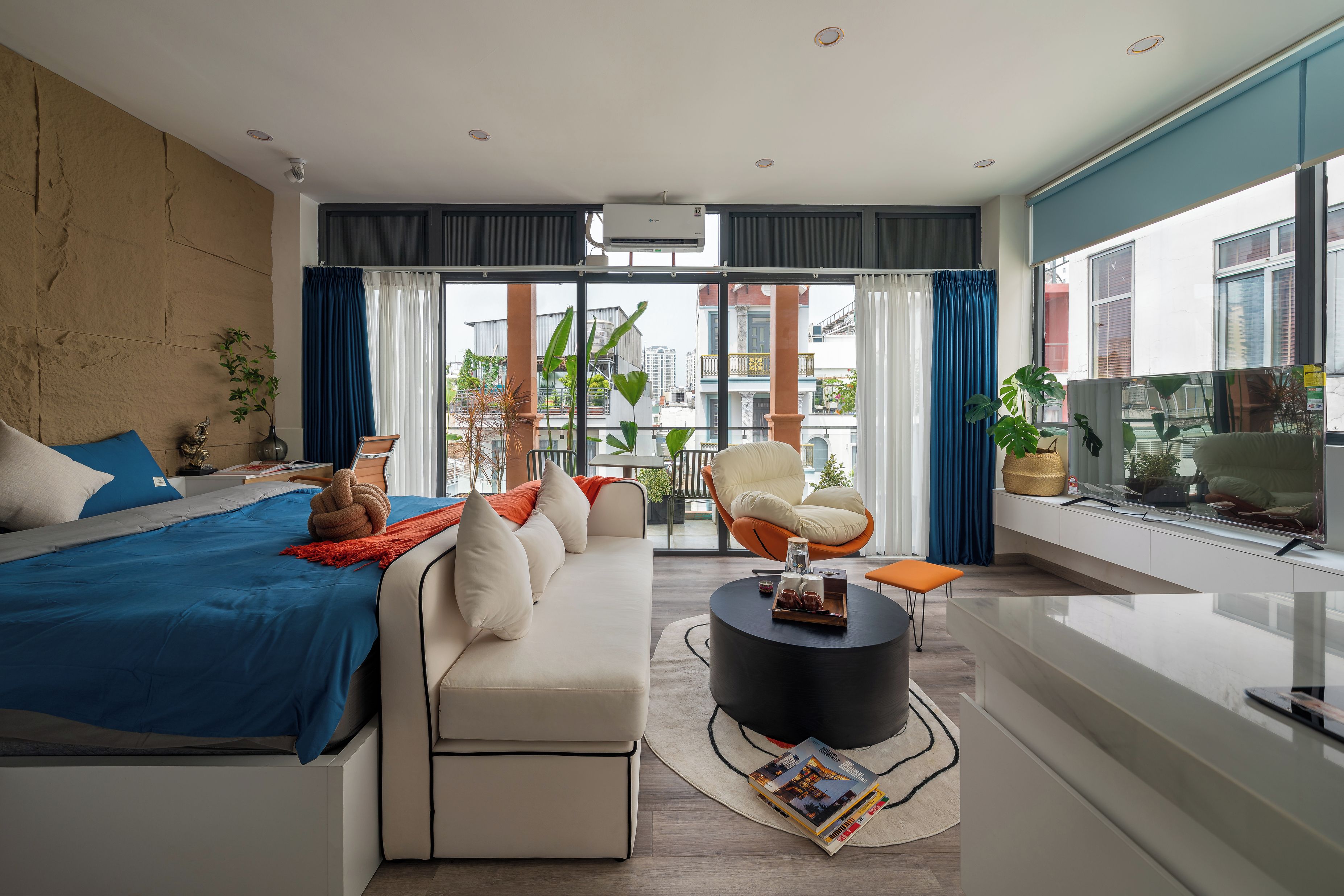 Une chambre moderne avec un grand lit, un canapé, un fauteuil et un coin repas.
