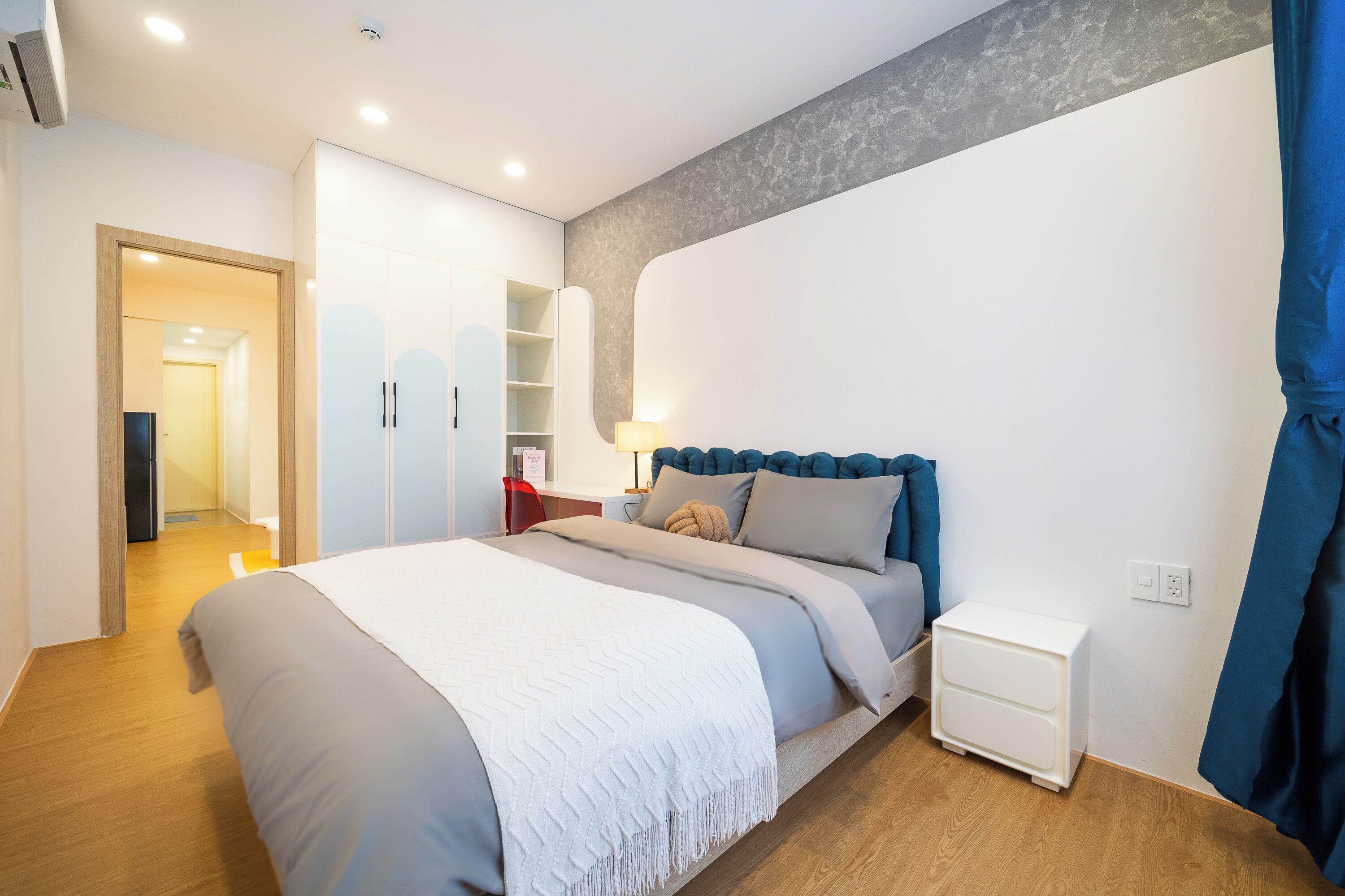 Un dormitorio con cama, mesitas de noche, armario y escritorio.