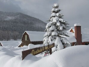 Ett snötäckt landskap med en träskylt som visar vägen till Redburn Ranch.