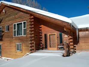 Eine Blockhütte mit verschneitem Dach und einer Veranda.