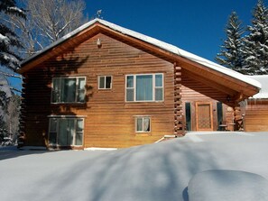 A log cabin with a snow-covered roof, large windows, and a visible door. - Dolores River "BIG House" 8BR Cabin 300-Acre Private Ranch (Dolores)