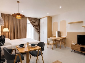 Una habitación de hotel con cama, escritorio, televisor y zona de comedor.