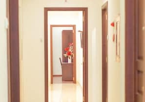 A hallway with a wooden door frame, a chair, and a vase with red flowers.