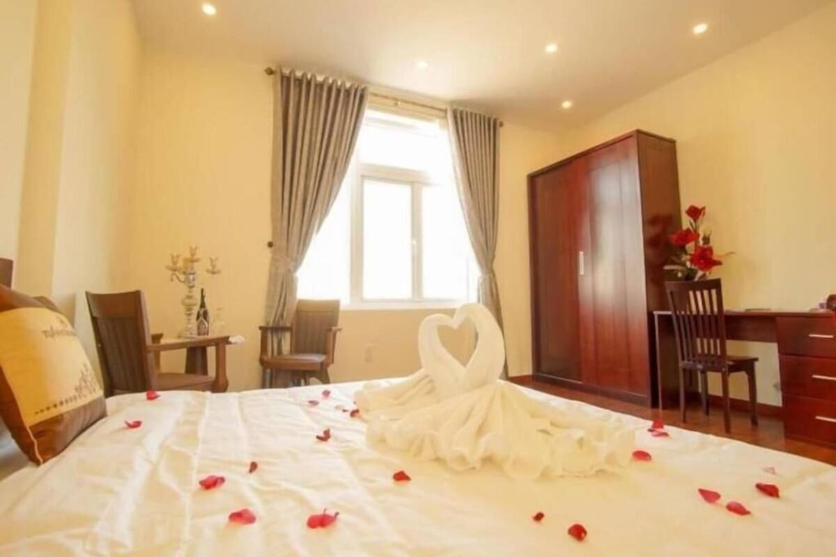 A hotel room with a bed, a desk, a wardrobe, and a window with curtains.
