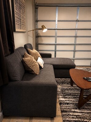 Ein modernes Wohnzimmer mit einer Eckcouch, einem Holztisch und einer Stehlampe.
