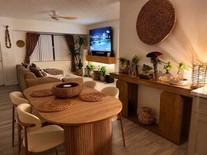 Ein modernes Wohnzimmer mit einem runden Holztisch, beigen Sofas und einem flachbildfernseher an der Wand.