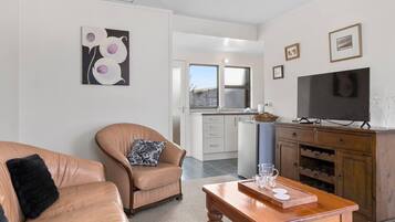 A living room with a leather sofa, a wooden coffee table, and a television on a wooden cabinet.