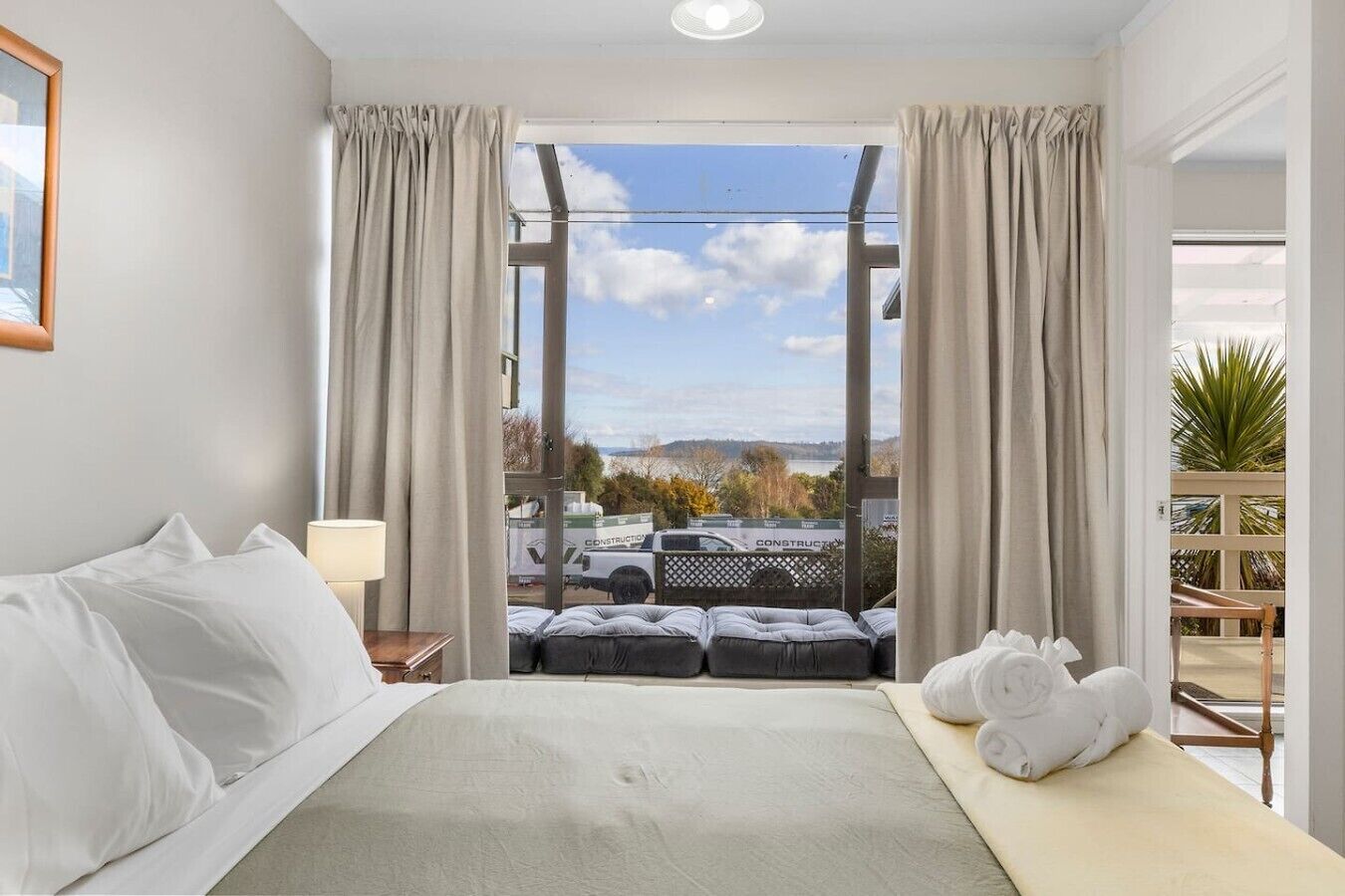 A hotel room with a bed, a view of the outside, and a balcony.