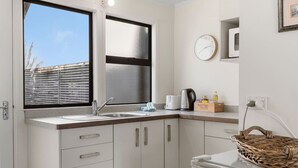 Eine kleine Küche mit Fenster, einer Spüle, einem Wasserkocher, einem Toaster und einem Korb.