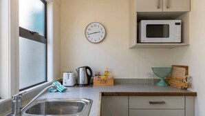 Eine Küche mit Spüle, Wasserkocher, Toaster, Mikrowelle, einer Uhr und einer Holzkiste mit der Aufschrift 'VETRO'.