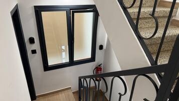 A staircase with a black metal railing, a window with a black frame, and a fire extinguisher on the wall.
