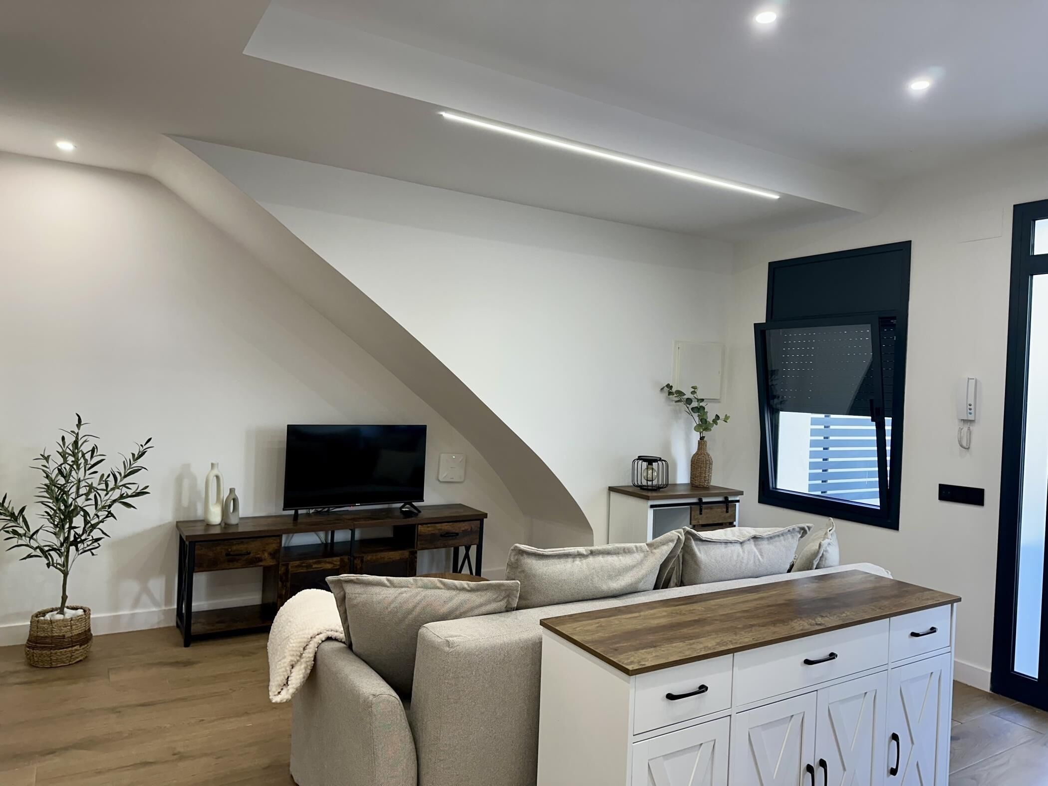 A modern living room with a TV, sofa, and wooden coffee table.
