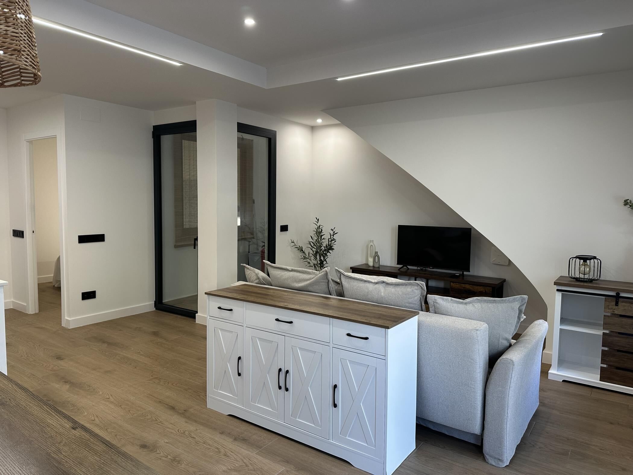 A modern living room with a sofa, a TV, and a wooden cabinet.