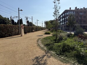 A pathway with a hedge on one side and a building on the other. - Ground floor with A/C and terrace only 250m beach (Calella)