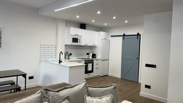 A modern kitchen with white cabinets, a built-in oven, and a microwave.