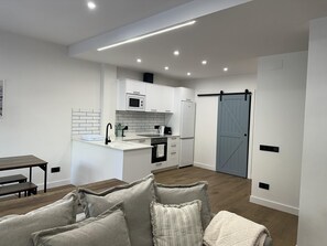 A modern kitchen with white cabinets, a built-in oven, and a microwave. - Ground floor with A/C and terrace only 250m beach (Calella)