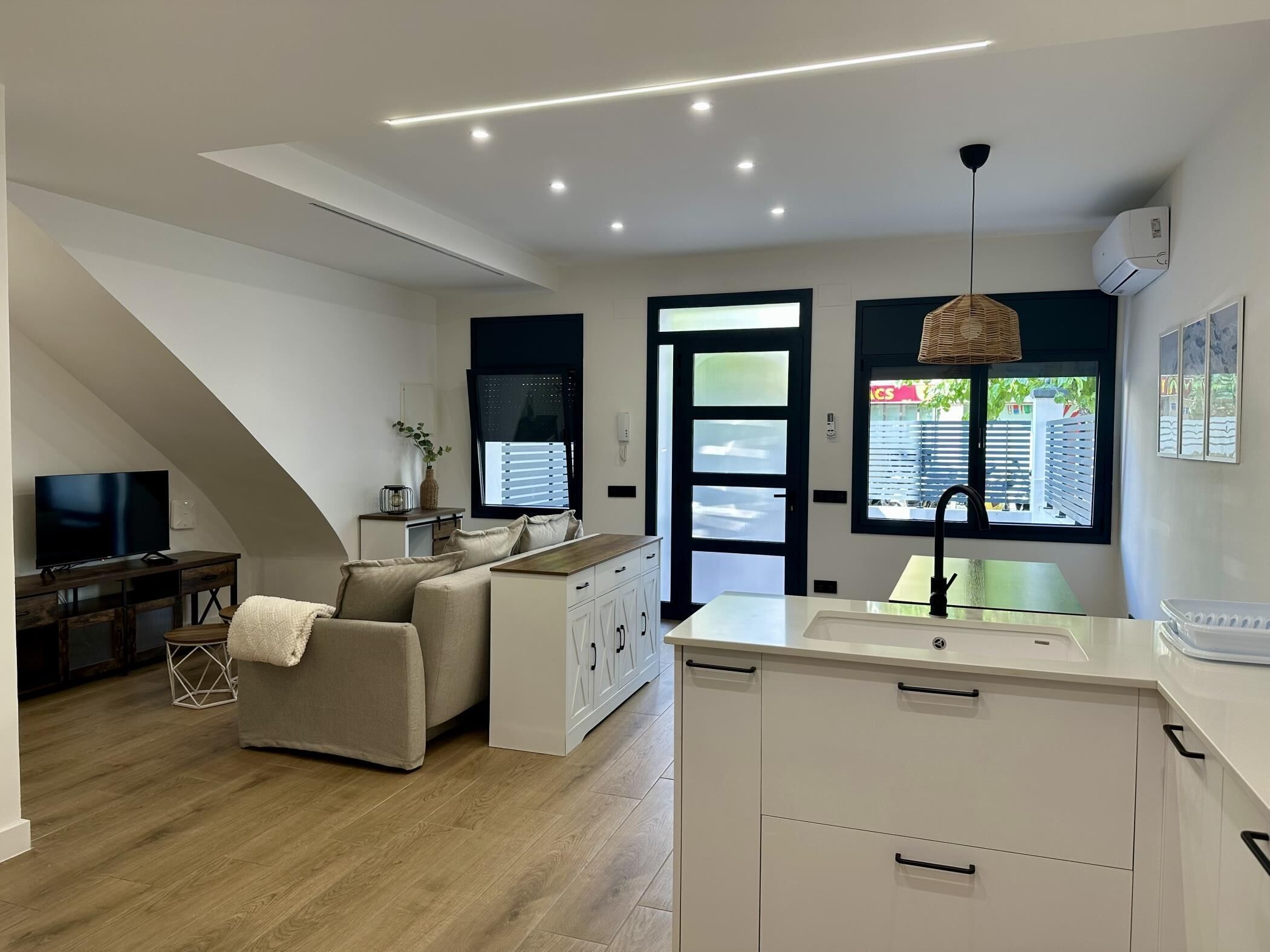 Un salon moderne comprenant un canapé, un téléviseur et un coin repas avec une table et des chaises.