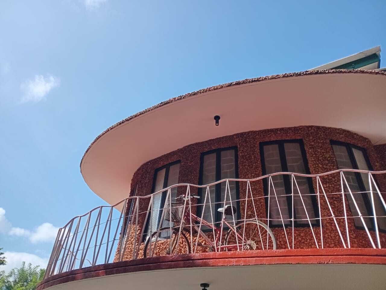 Un edificio con un balcón curvo, barandilla metálica y ventanas.