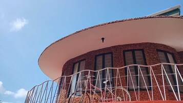 Un edificio con un balcón curvo, barandilla metálica y ventanas.