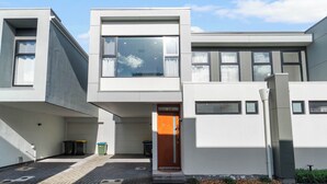 Een modern gebouw met twee verdiepingen, een plat dak, grote ramen en een duidelijke deur.
