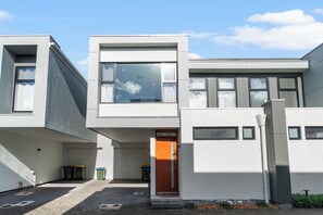 Ein modernes, zweistöckiges Gebäude mit flachem Dach, großen Fenstern und einer sichtbaren Tür.