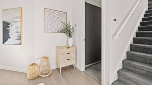 A modern interior with a staircase, a wooden cabinet, and two wall-mounted artworks. - Campbelltown modern home Family Stay (Campbelltown)