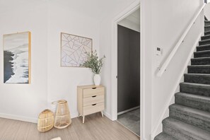 A modern interior with a staircase, a wooden cabinet, and two wall-mounted artworks. - Campbelltown modern home Family Stay (Campbelltown)