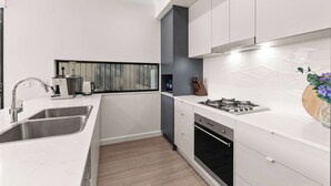 A modern kitchen with a stainless steel sink, a built-in oven, and a gas stove. - Campbelltown modern home Family Stay (Campbelltown)