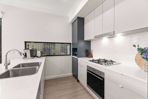 A modern kitchen with a stainless steel sink, a built-in oven, and a gas stove. - Campbelltown modern home Family Stay (Campbelltown)