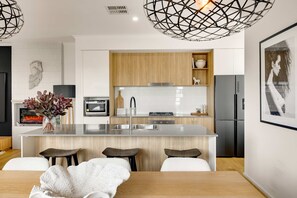 Eine moderne Küche mit Kochinsel, Holzschränken, Edelstahlgeräten und einem dekorativen Pferdekopf an der Wand.
