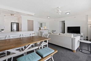 Ein modernes Wohnzimmer mit Essbereich, einer Couch und einem Fernseher.
