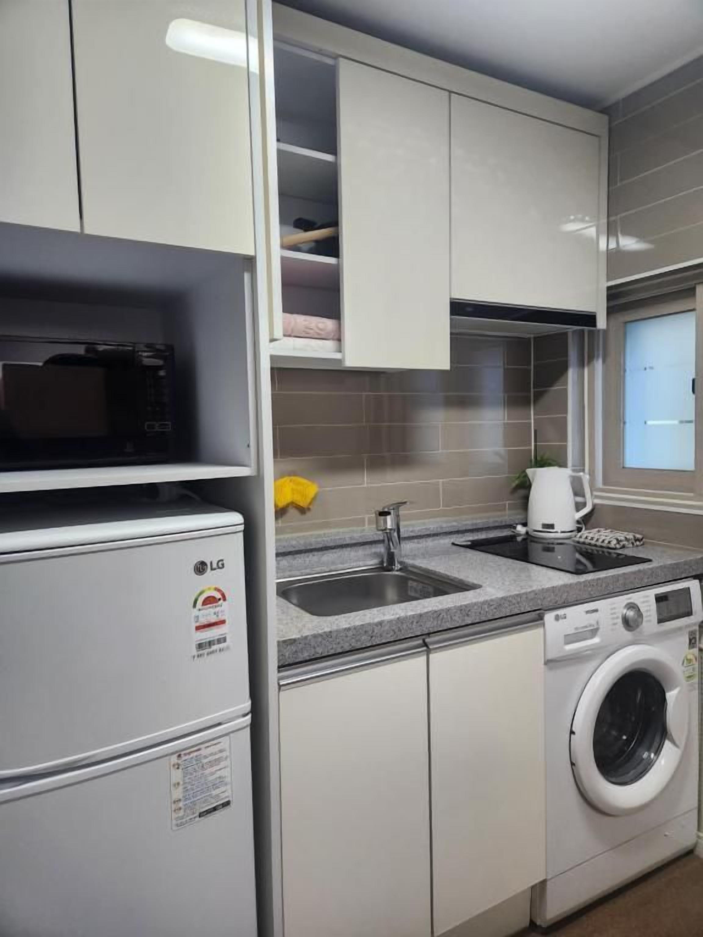 A compact kitchen with a microwave, washing machine, and a coffee maker.