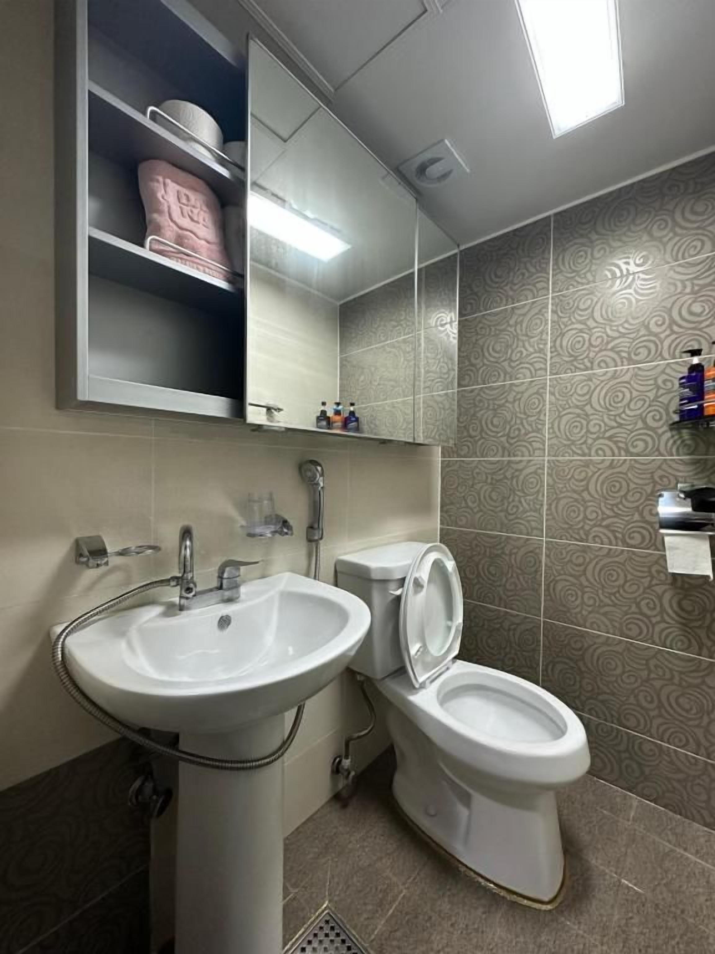 A bathroom with a pedestal sink, a toilet, and a mirror above the sink.