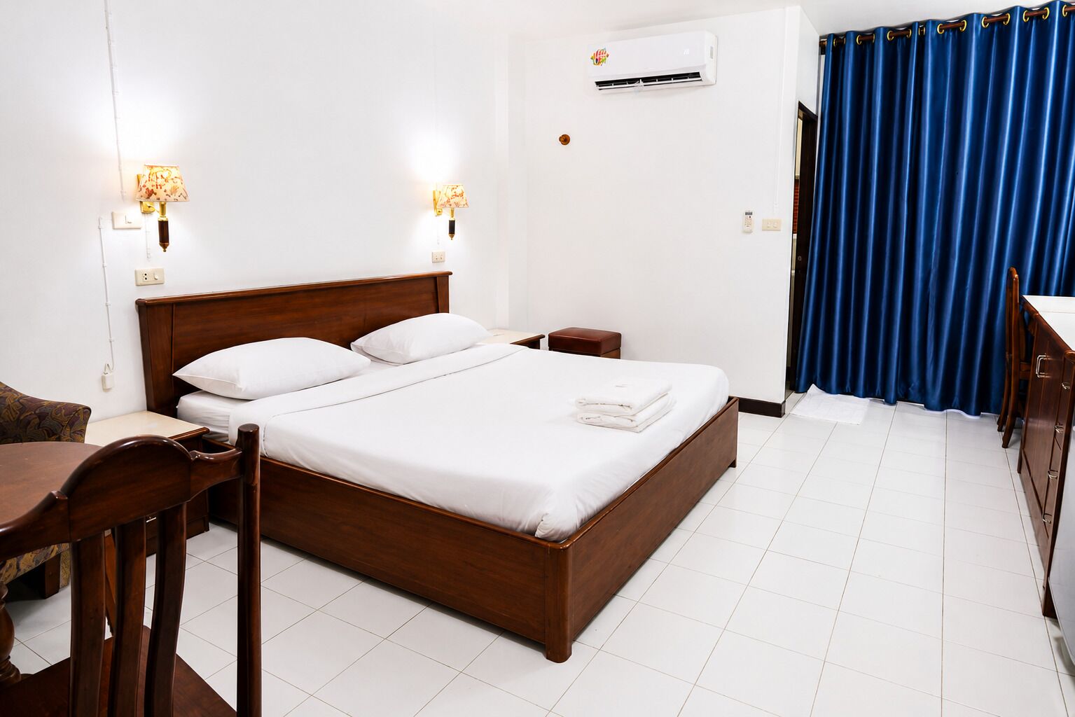 Une chambre d’hôtel avec un lit en bois, des tables de chevet, un bureau et une chaise.