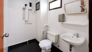 A small bathroom with a toilet, a sink, a shower, and a hand dryer.
