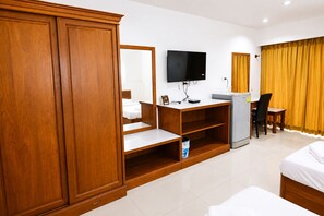 A hotel room with a wooden wardrobe, a flat-screen TV, a desk with a chair, and a bed.