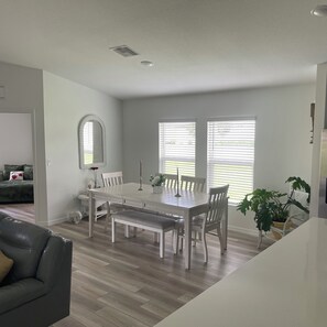 Un comedor con una mesa y sillas blancas, un banco y una planta en maceta.