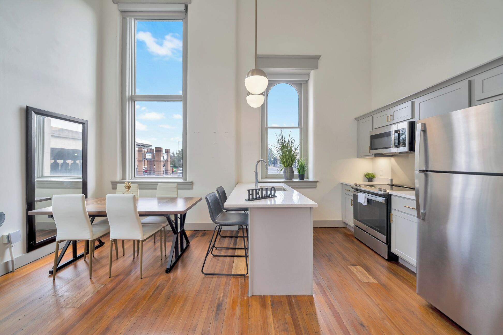 A modern kitchen with a central island, stainless steel appliances, and large windows.