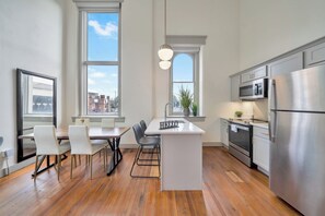 A modern kitchen with a central island, stainless steel appliances, and large windows. - Modern City Loft - Nearby Parking - Downtown - 2F (Louisville)
