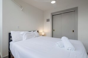 A hotel room with a bed, a nightstand, a lamp, a door, and a ceiling light. - Modern City Loft - Nearby Parking - Downtown - 2F (Louisville)