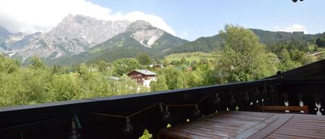 A balcony with a view of a mountain range and a small building in the distance.