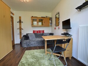 Ett kompakt vardagsrum med en soffa, ett litet träbord, en tv och ett element.