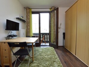 Een kamer met een houten bureau, zwarte stoelen, een televisie en een groen tapijt.
