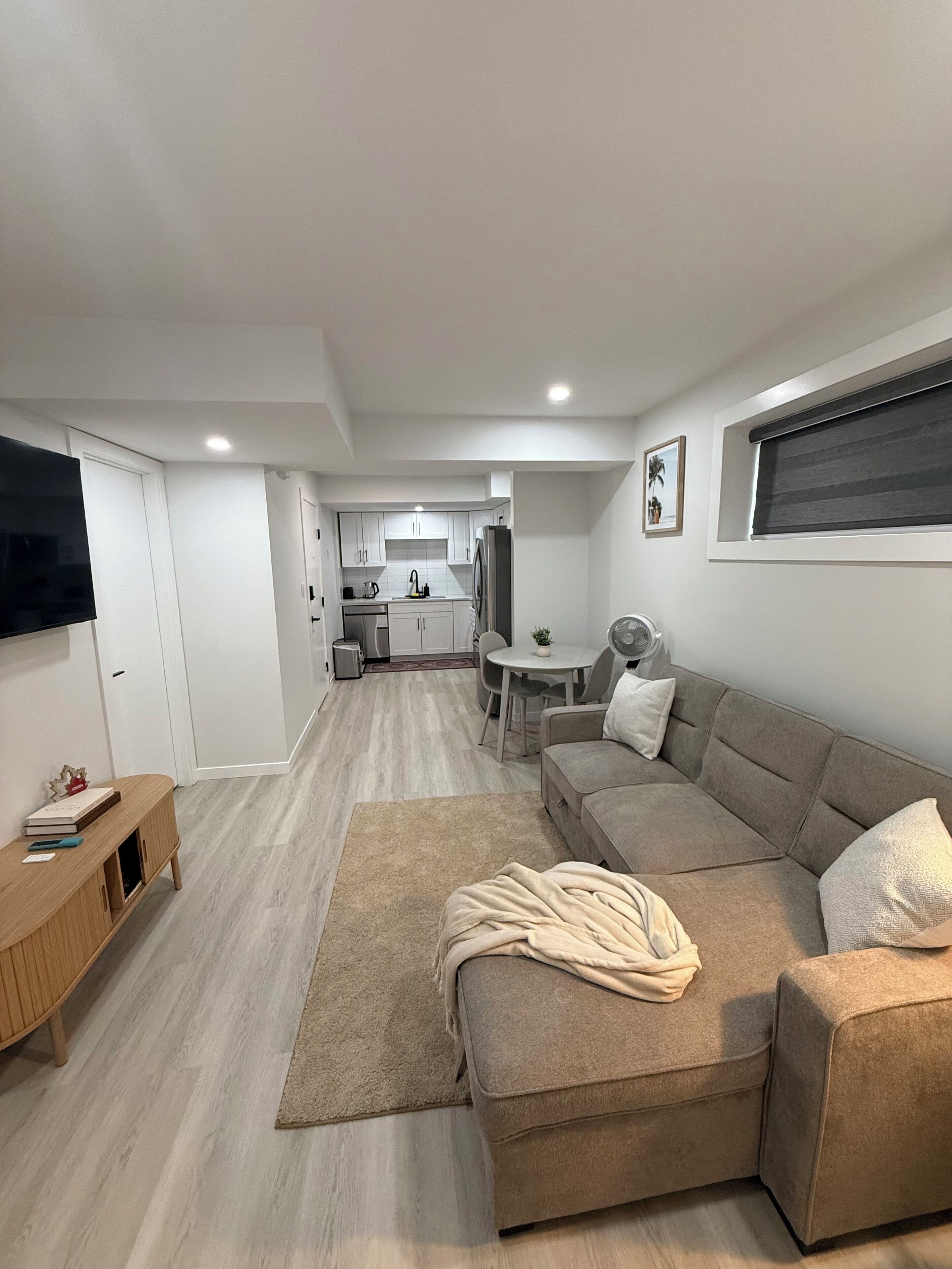 A modern living room with a sofa, a TV, and a wooden side table.