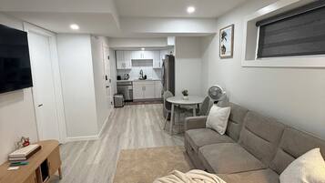 A modern living room with a sofa, a TV, and a wooden side table.