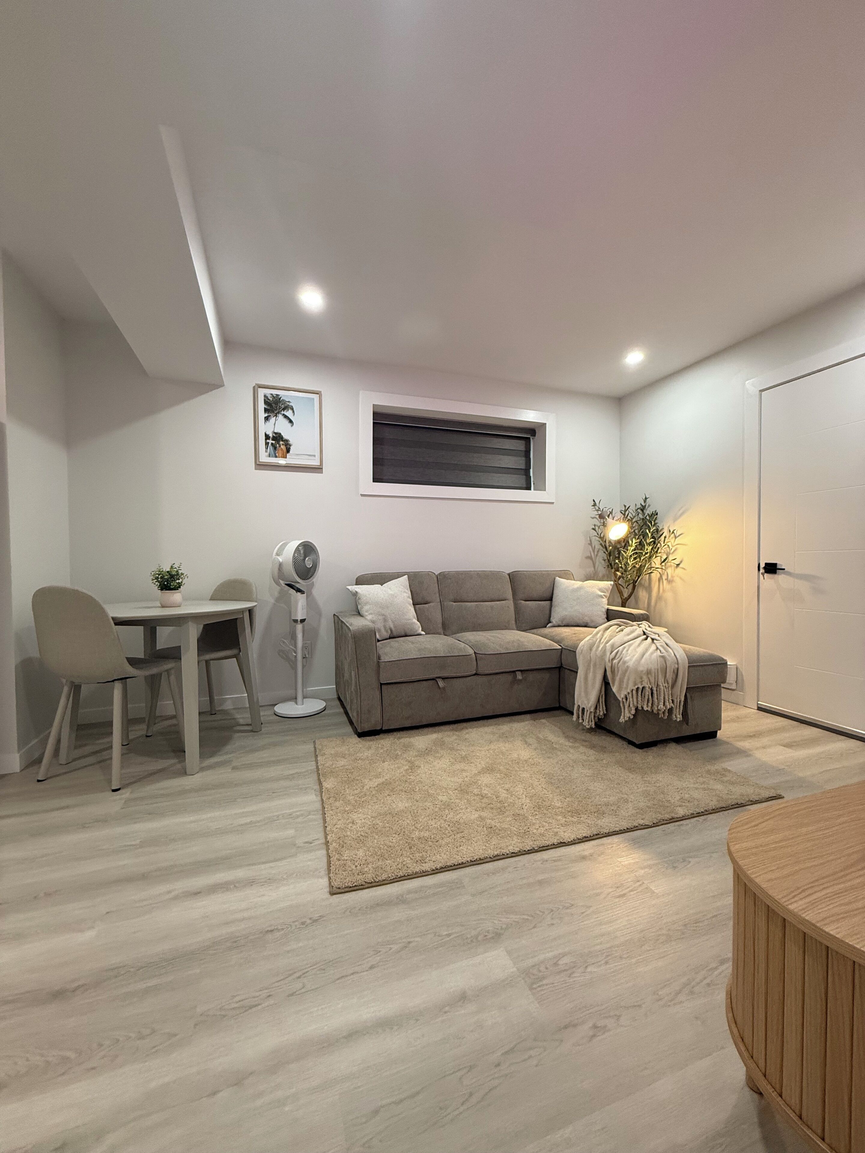 Ein modernes Wohnzimmer mit einem grauen Sofa, einem kleinen Tisch und einer Stehlampe.