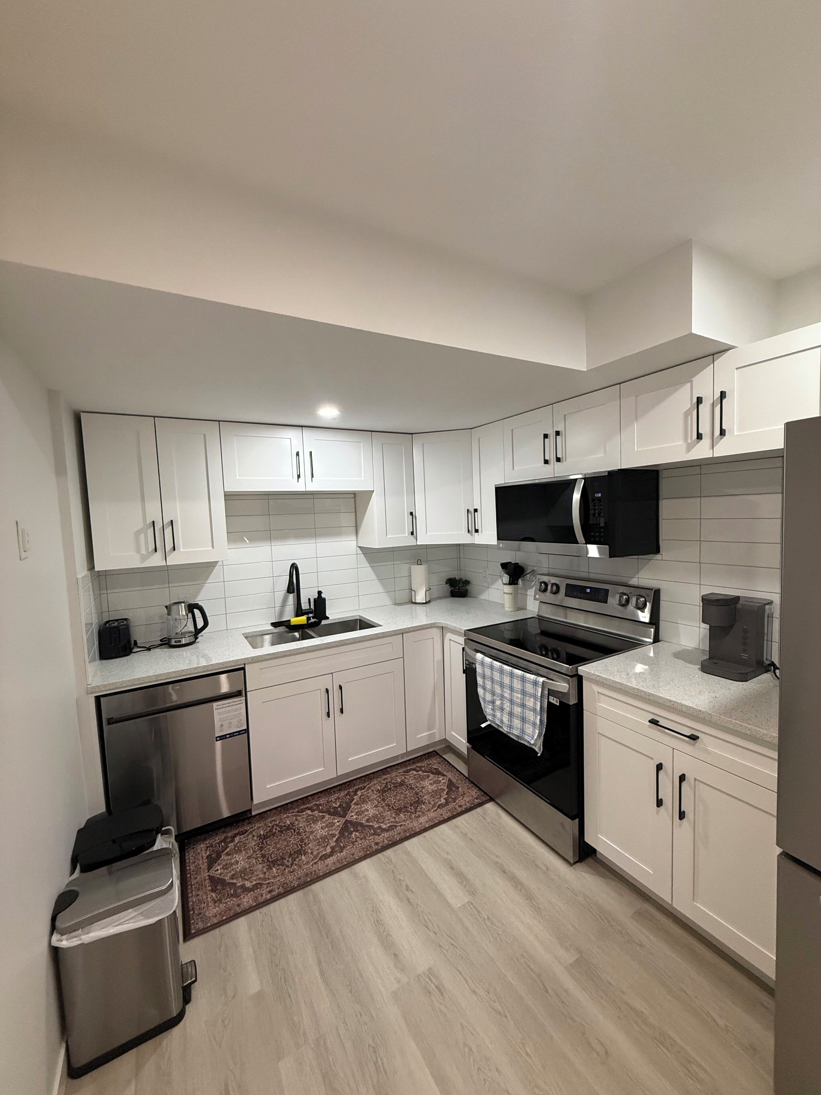 Una cocina moderna con armarios blancos, electrodomésticos de acero inoxidable y un salpicadero de azulejos.
